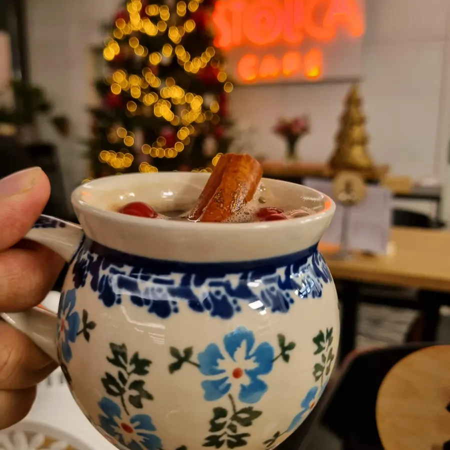 Świąteczny napój w ceramicznym kubku, w tle choinka